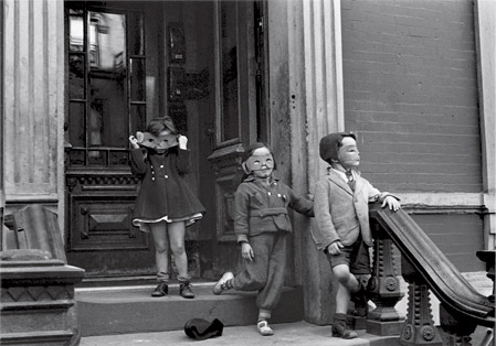 plano general de tres niños con una máscara posando en la puerta de una casa